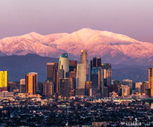 Panoramic view of downtown Los Angeles skyline with snow-capped San Gabriel Mountains, representing Millennial Security Inc.'s security guard services in the City of Los Angeles.