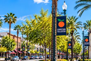 Bright daytime panoramic view of Downtown Fullerton featuring Fox Fullerton Theatre, Fullerton Transportation Center, historic buildings and palm-lined streets in Fullerton, Orange County, California.