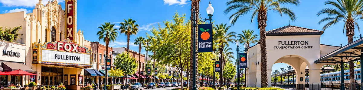 Bright daytime panoramic view of Downtown Fullerton featuring Fox Fullerton Theatre, Fullerton Transportation Center, historic buildings and palm-lined streets in Fullerton, Orange County, California.