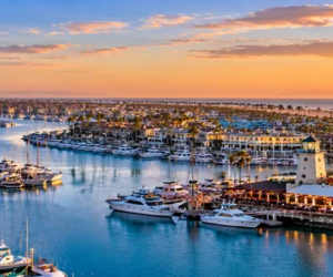 Aerial panoramic illustration of Channel Islands Harbor, boats, waterfront neighborhoods, and Pacific Ocean at sunset in Oxnard, Ventura County, California.