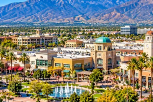 Bright daytime aerial illustration of Victoria Gardens shopping district, palm-lined streets, and San Gabriel Mountains in Rancho Cucamonga, California.