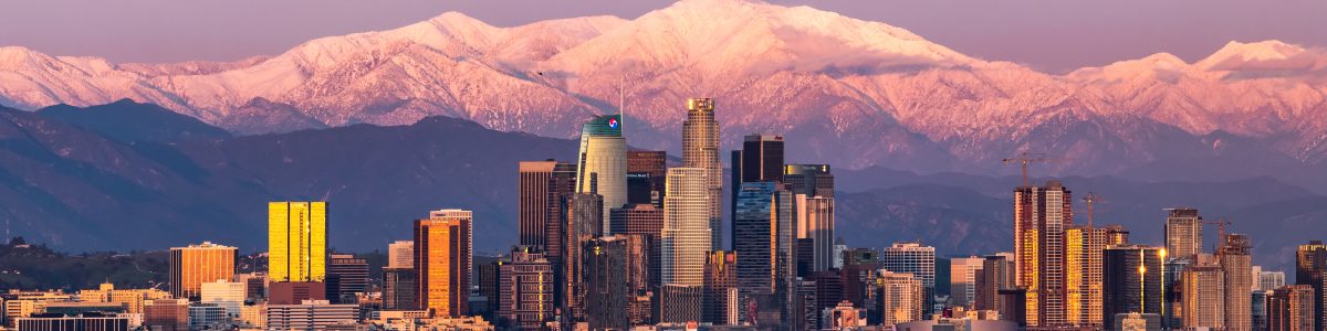 Panoramic view of downtown Los Angeles skyline with snow-capped San Gabriel Mountains, representing Millennial Security Inc.'s security guard services in the City of Los Angeles.